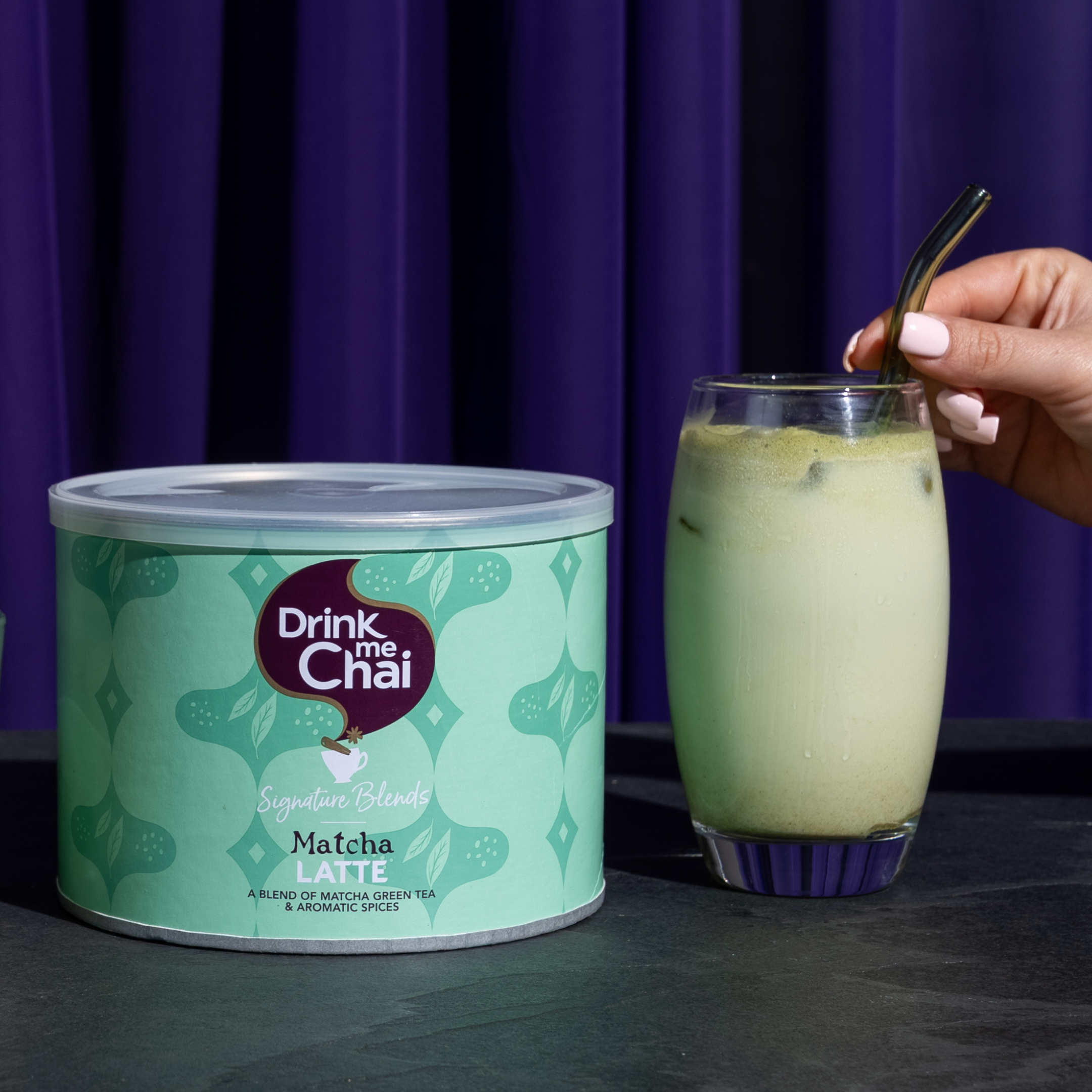 1kg matcha spiced chai latte packshot alongside made-up iced matcha drink with straw
